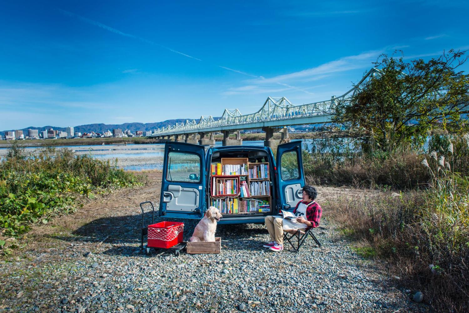 A moving bookstore and a dog on the river side.